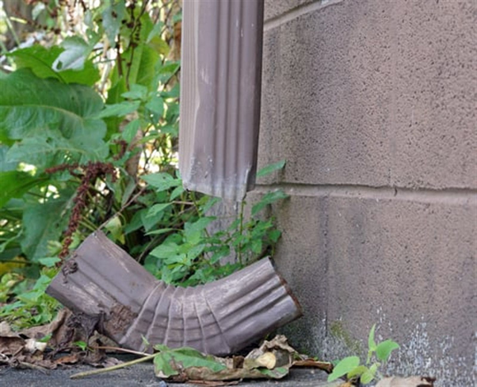 Detached downspout section pulled away from a home's exterior wall